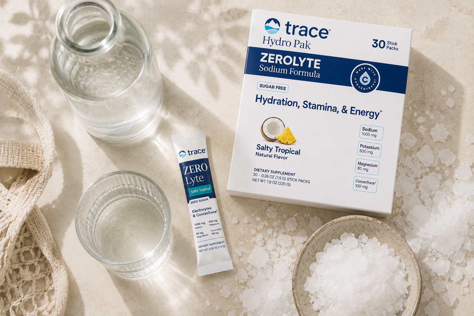 Close-up of a glass of water with a lemon slice beside a stone dish of coarse sea salt on a sunlit windowsill